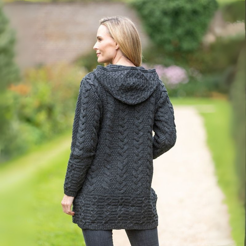 Woman wearing a dark gray hooded jacket with cable knit pattern in an outdoor setting.
