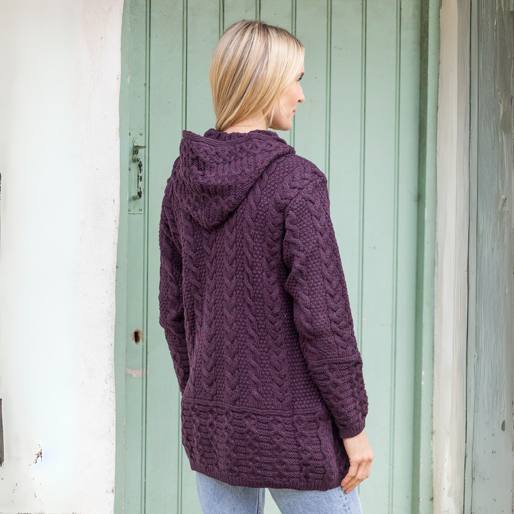 Woman wearing a purple knitted hoodie standing in front of a green door.