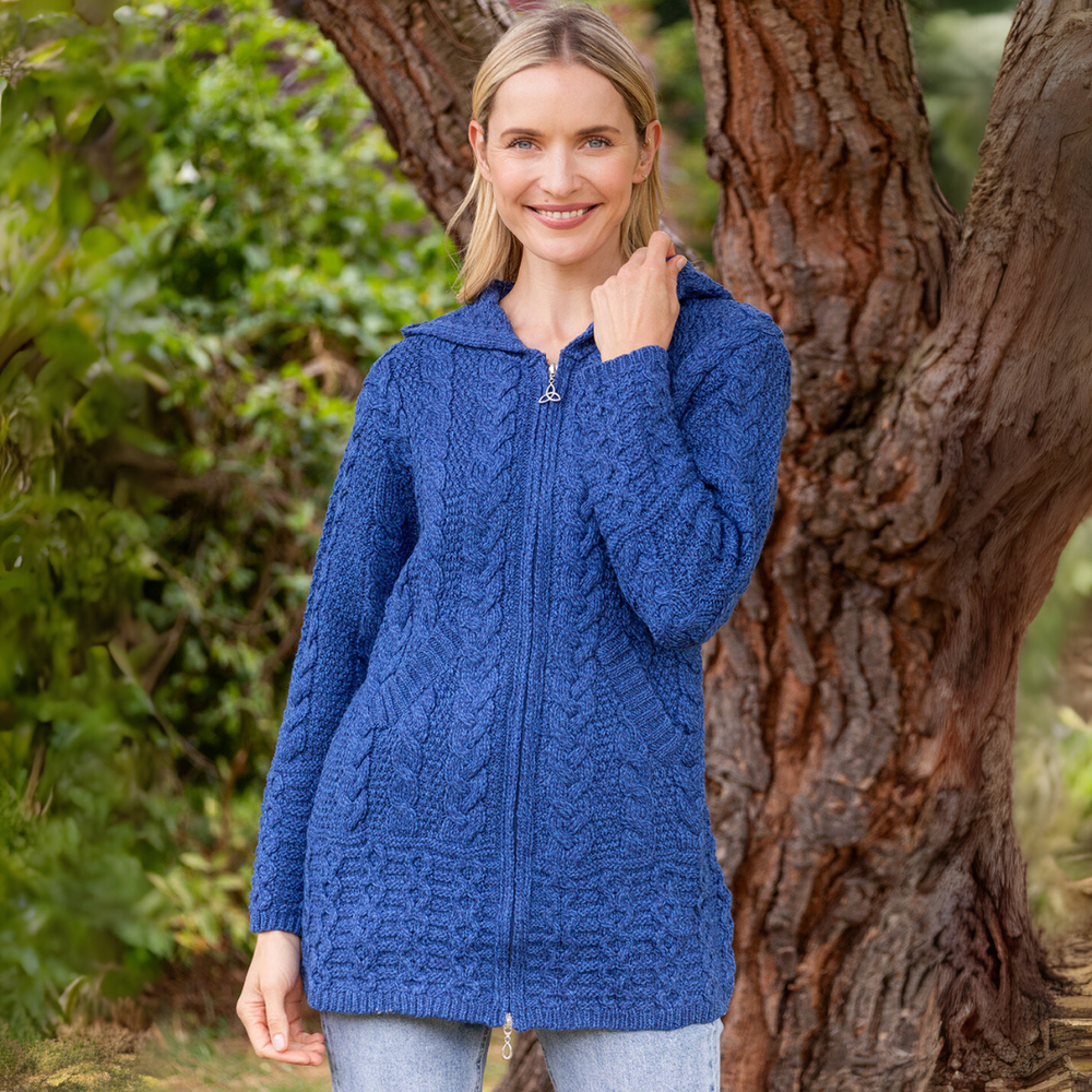 Woman wearing a blue knitted jacket standing next to a tree
