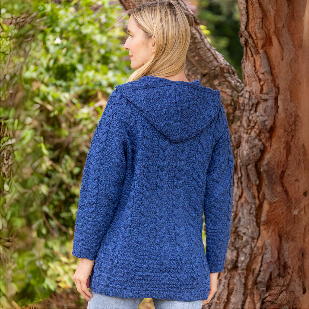 Woman wearing a blue knitted hoodie standing next to a tree