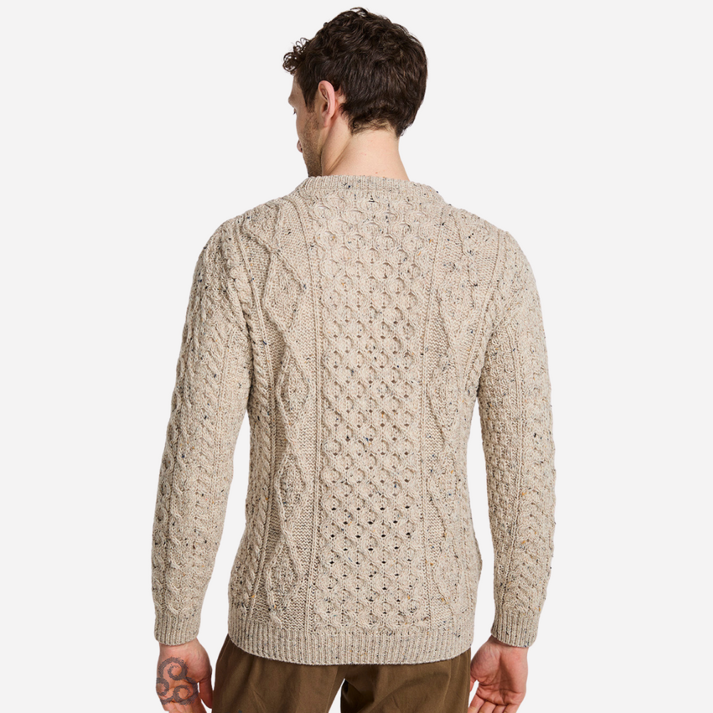 Man wearing a beige cable knit sweater on a white background