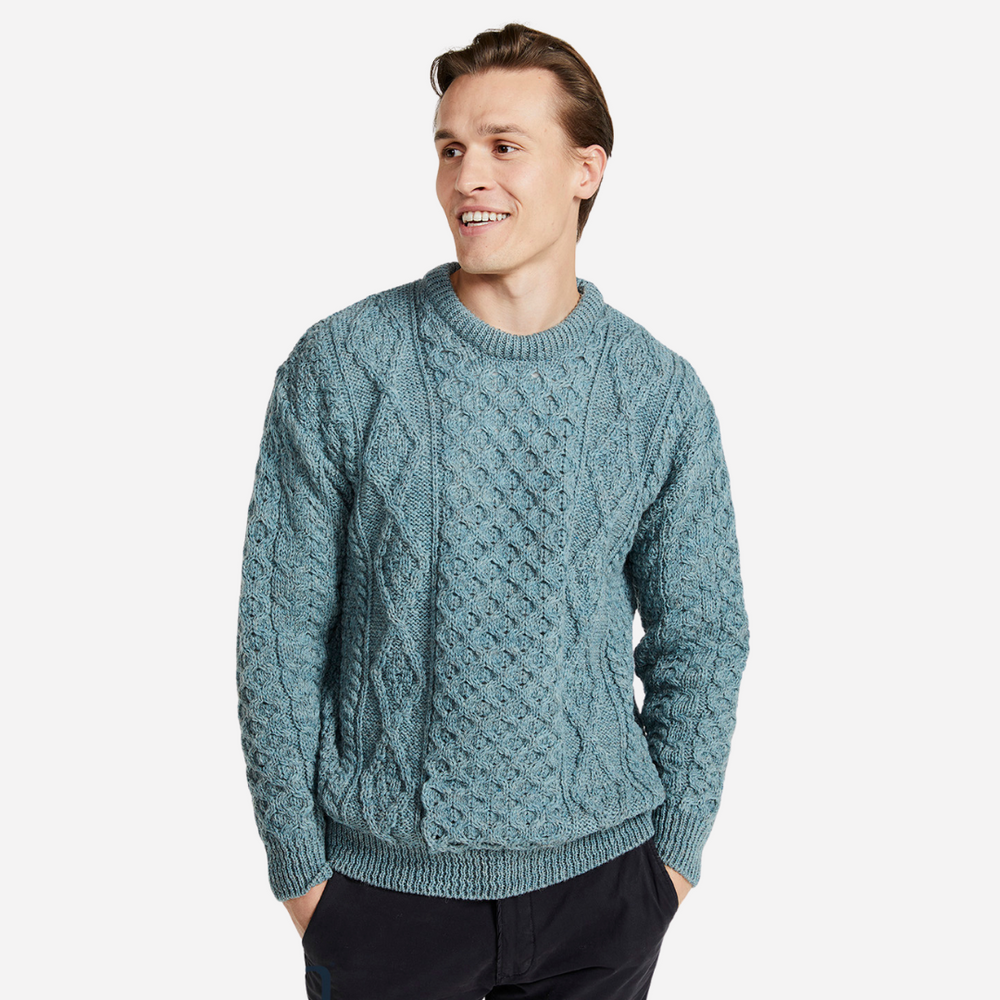 Man wearing a teal cable knit sweater on a white background