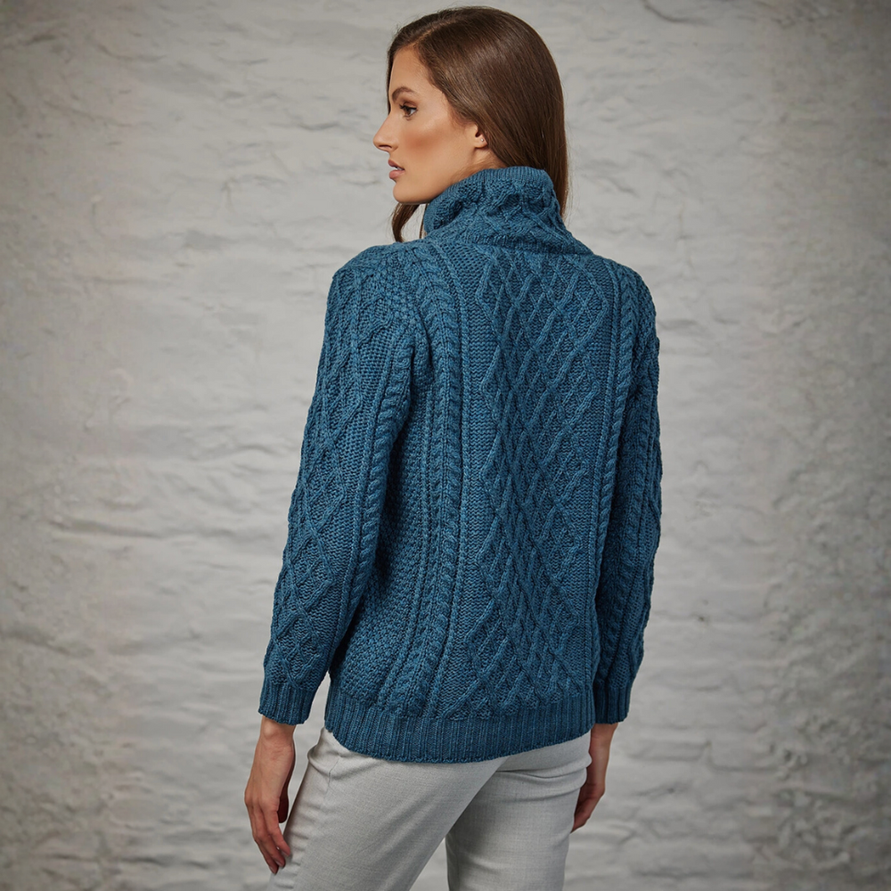 Woman wearing a blue knitted sweater against a gray textured wall