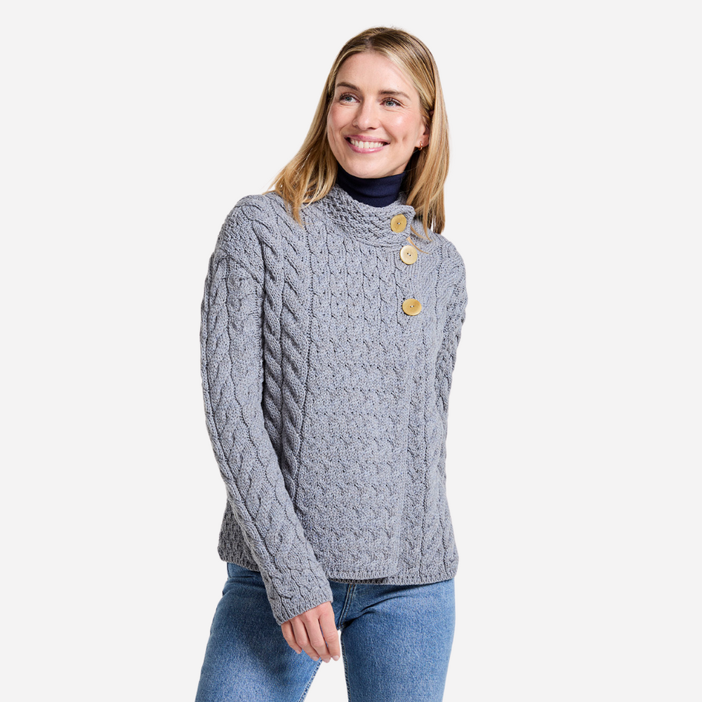 Woman wearing a gray cable knit sweater with button details on a white background
