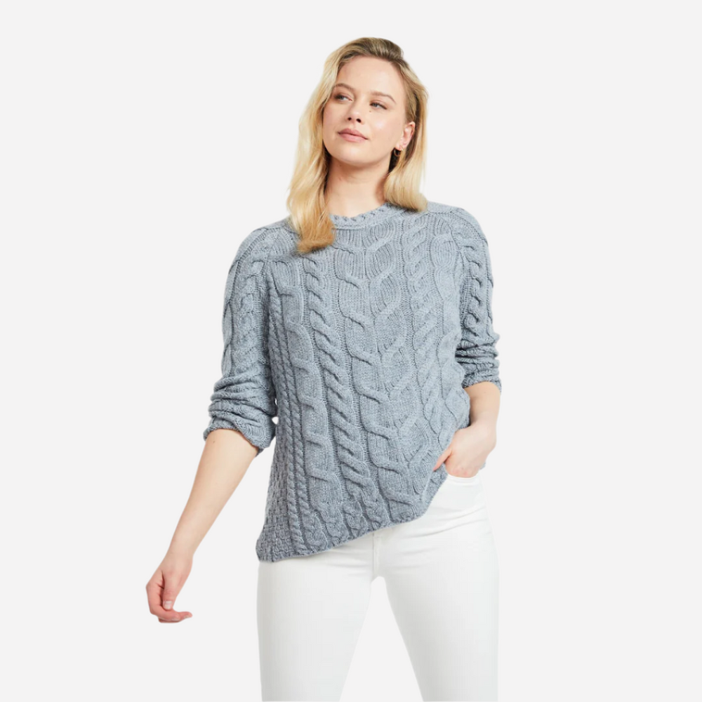 Woman wearing a gray cable knit sweater on a white background