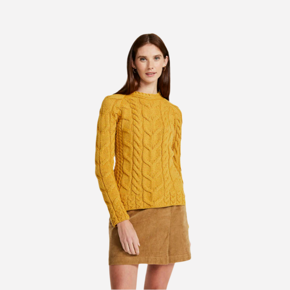 Woman wearing a mustard yellow cable knit sweater on a white background
