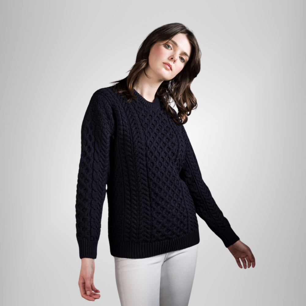 A woman wearing a navy Aran wool traditional merino sweater, standing against a neutral background.