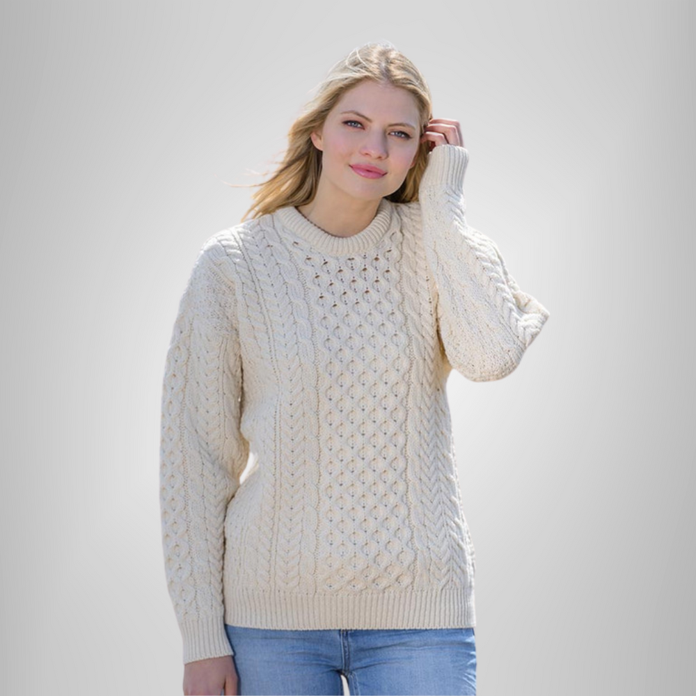 A woman wearing a traditional Aran wool sweater in white, featuring intricate cable patterns.