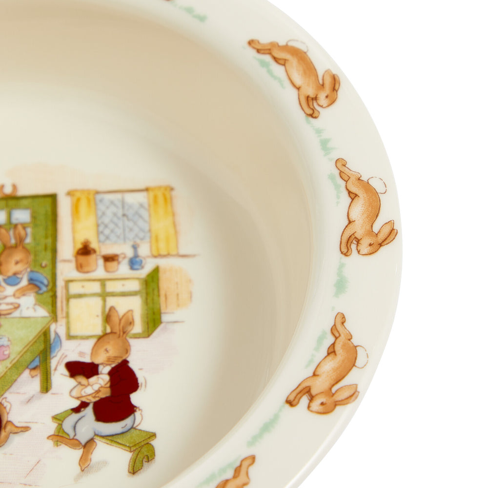 Ceramic bowl with illustrations of rabbits in a kitchen setting.
