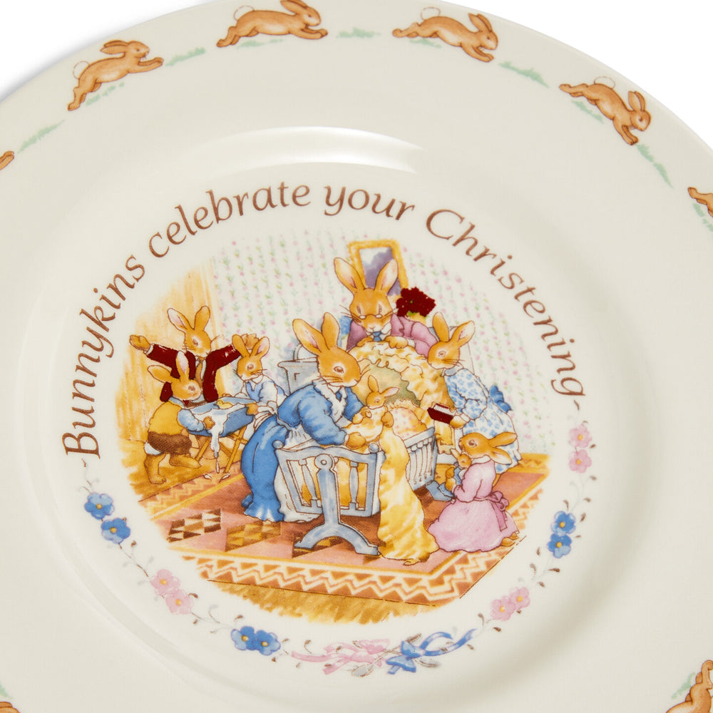 Decorative plate with rabbit illustrations and text, featuring a Christening scene.