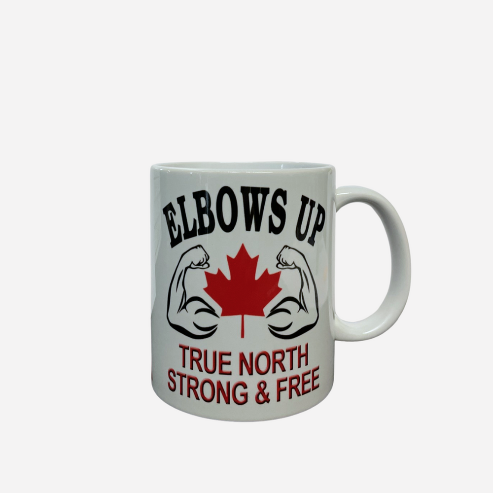 A white ceramic mug with 'ELBOWS UP TRUE NORTH STRONG & FREE' text and a graphic of a maple leaf and a fist.