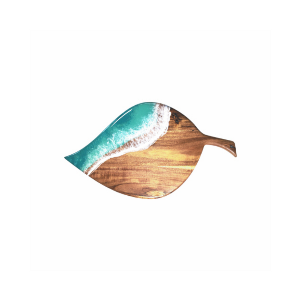 A leaf-shaped cheese board made of rustic Acacia hardwood with a blue epoxy accent resembling a seashore on the top.