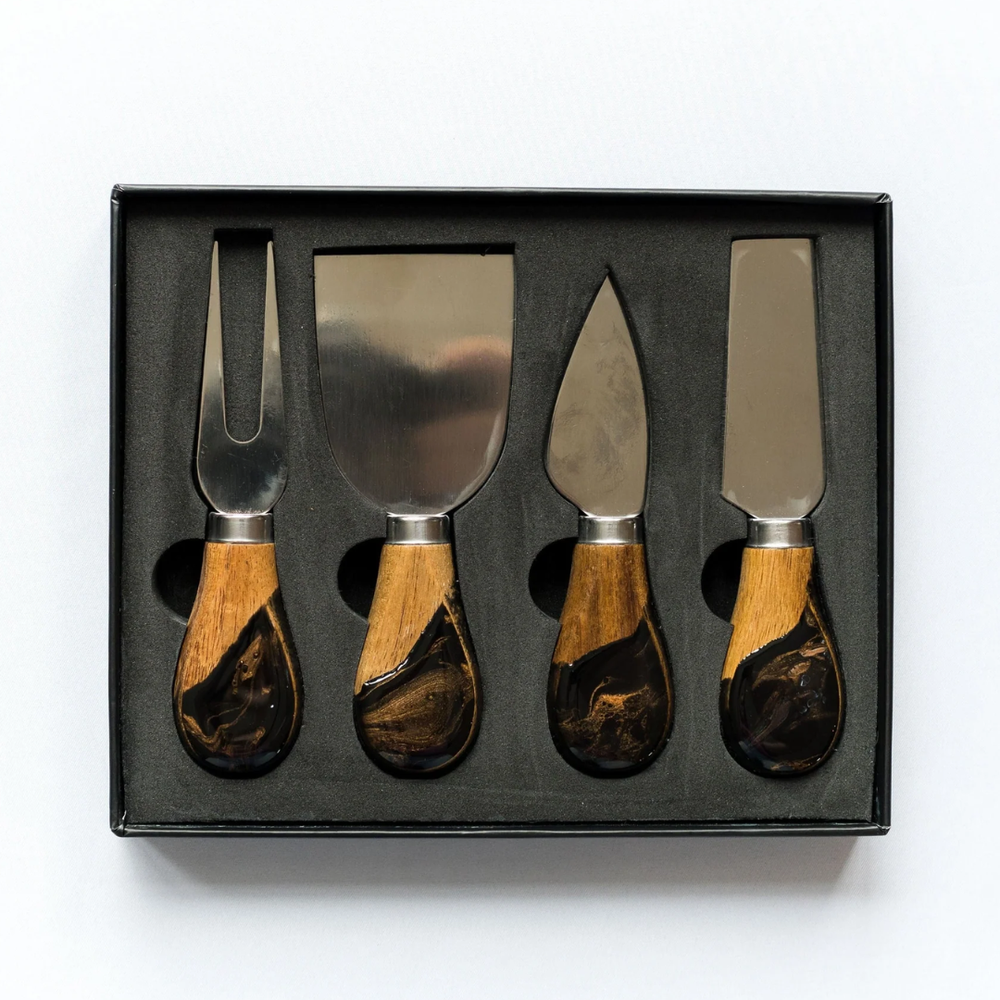 A set of four cheese knives with wooden handles and stainless steel blades, displayed in a black box.