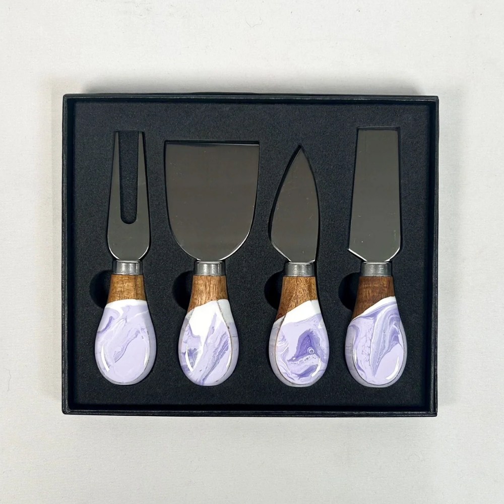 A set of four cheese knives with wooden lavender marble epoxy handles and stainless steel blades, displayed in a black box.