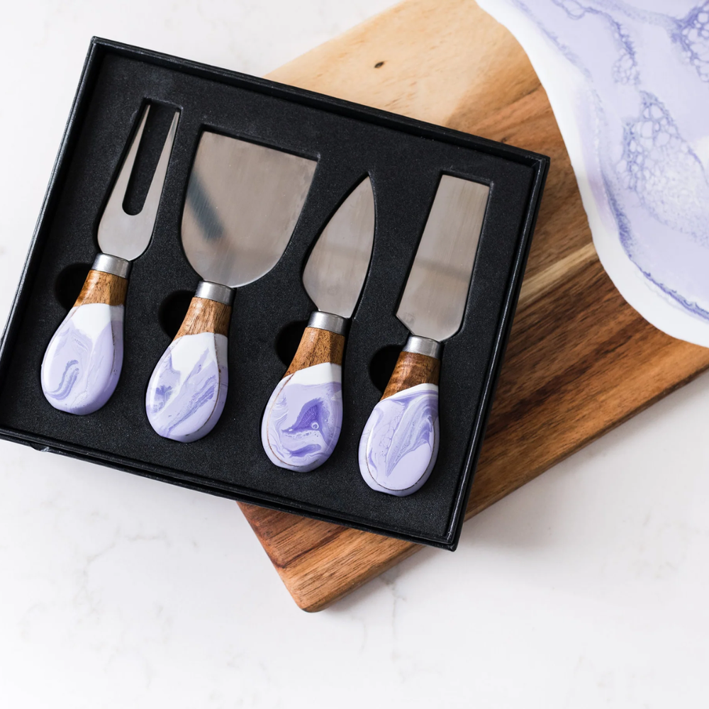 A set of four cheese knives with wooden lavender marble epoxy handles and stainless steel blades, displayed in a black box.
