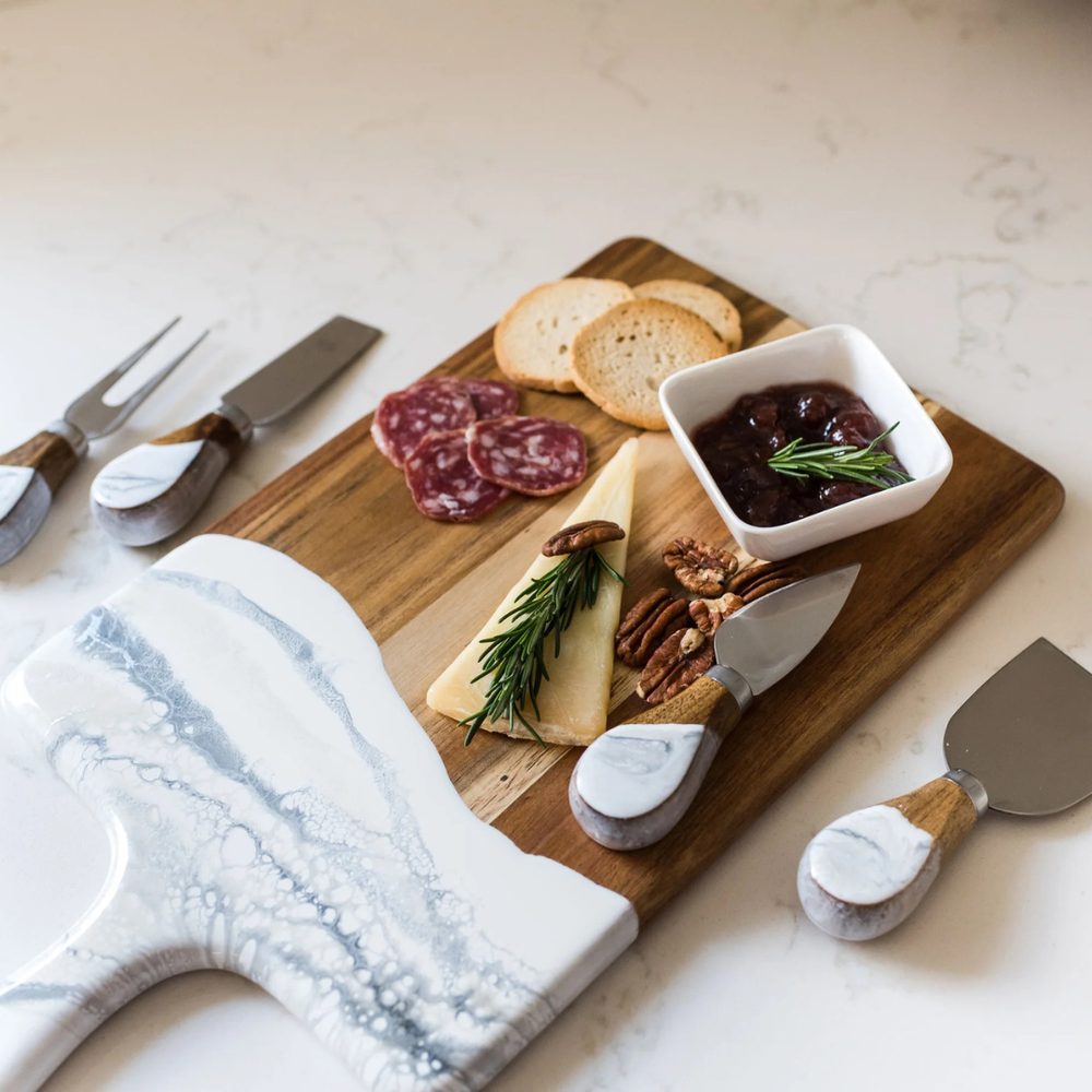 A set of four cheese knives with wooden handles and stainless steel blades, displayed on serving board.