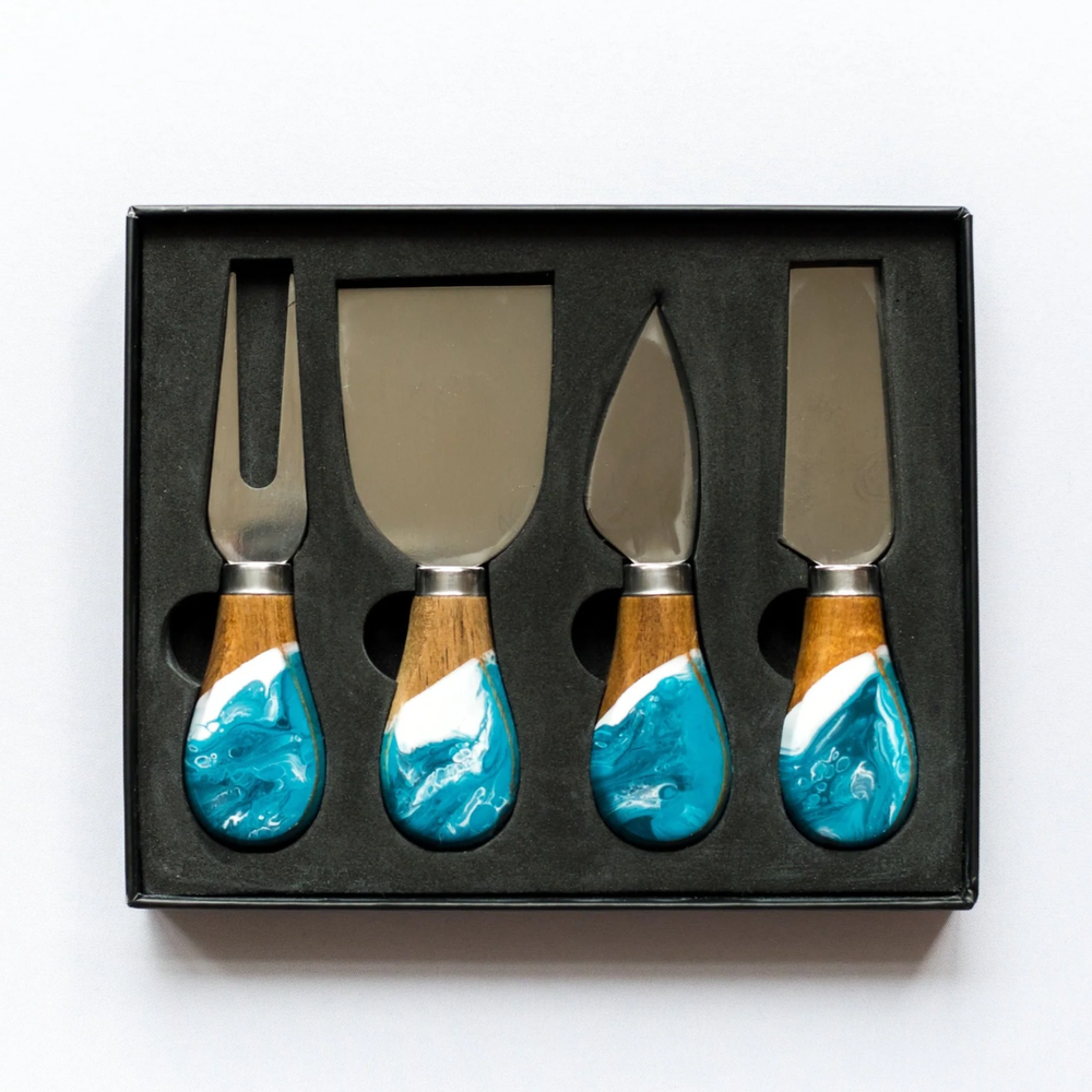 A set of four cheese knives with wooden handles and stainless steel blades, displayed in a black box.