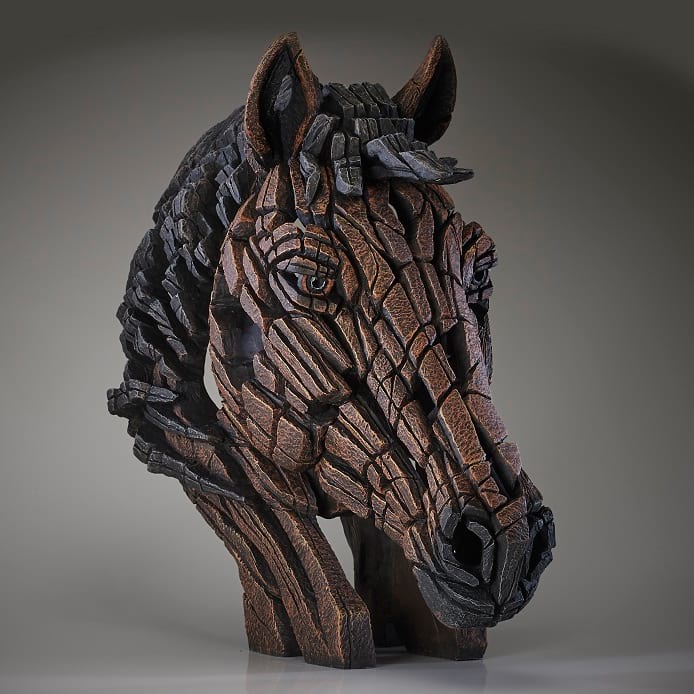 A detailed sculpture of a horse's head with a mix of brown, black, and beige colors, designed by Matt Buckley.