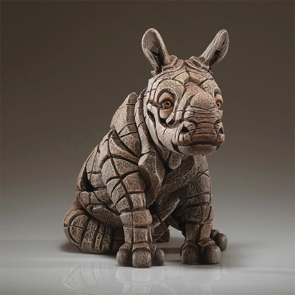 Stone sculpture of a rhinoceros on a neutral background