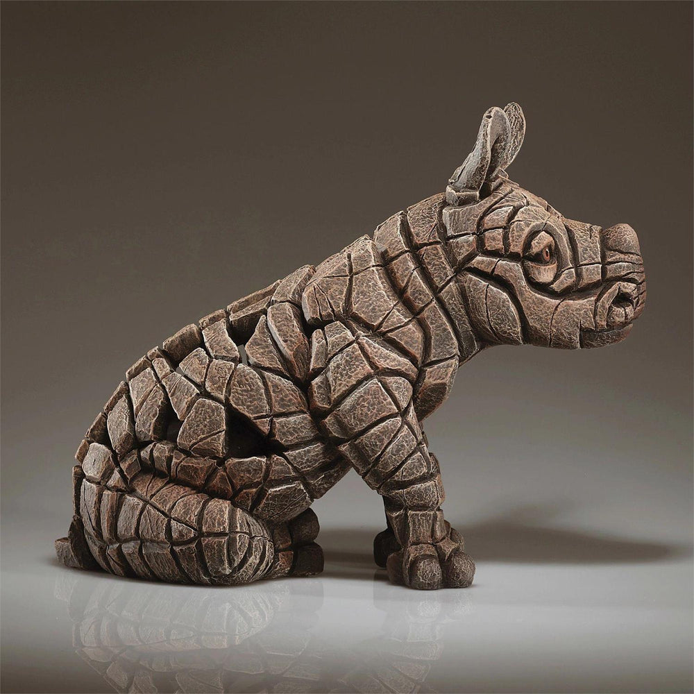 Stylized rhinoceros sculpture with geometric pattern on a reflective surface