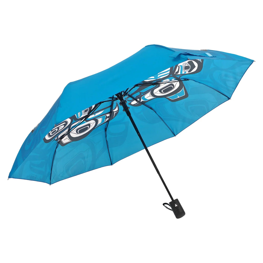 Blue umbrella with a black handle and strap on a white background