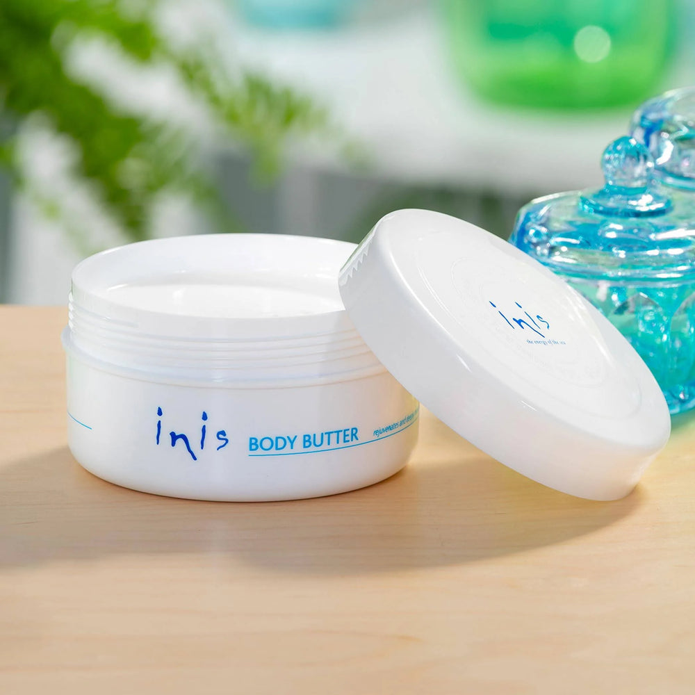 Open jar of inis body butter on a wooden surface with blurred background