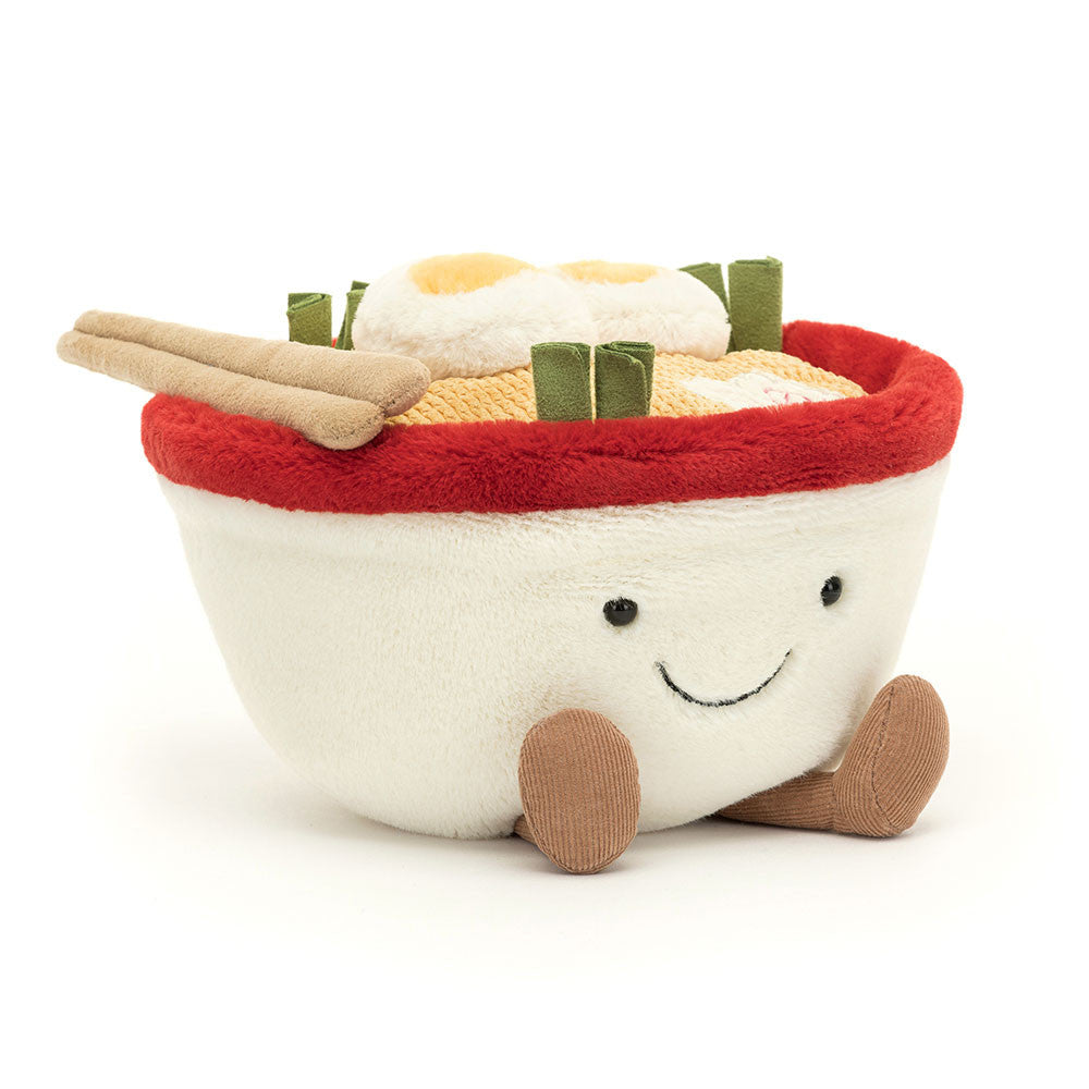 A plush toy resembling a ramen dish with a smiling face, cream-and-red bowl, suedette chopsticks, and decorative elements like spring onions and a fish cake.