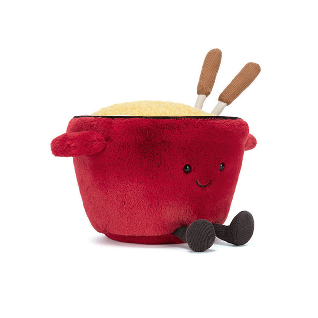 Plush toy resembling a red pot with a face, yellow contents, and wooden spoons on a white background
