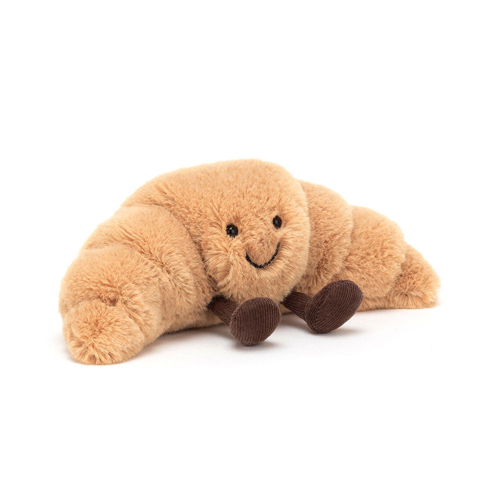 A small plush toy resembling a croissant with a smiling face and brown feet.