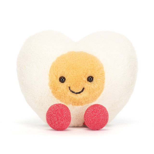 Round plush toy with a smiling face, beige body, pink legs, and white background