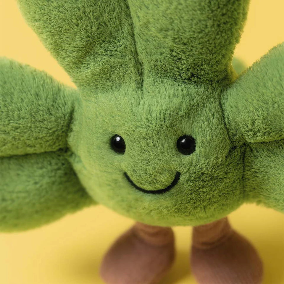 Green plush toy with a smiling face on a yellow background