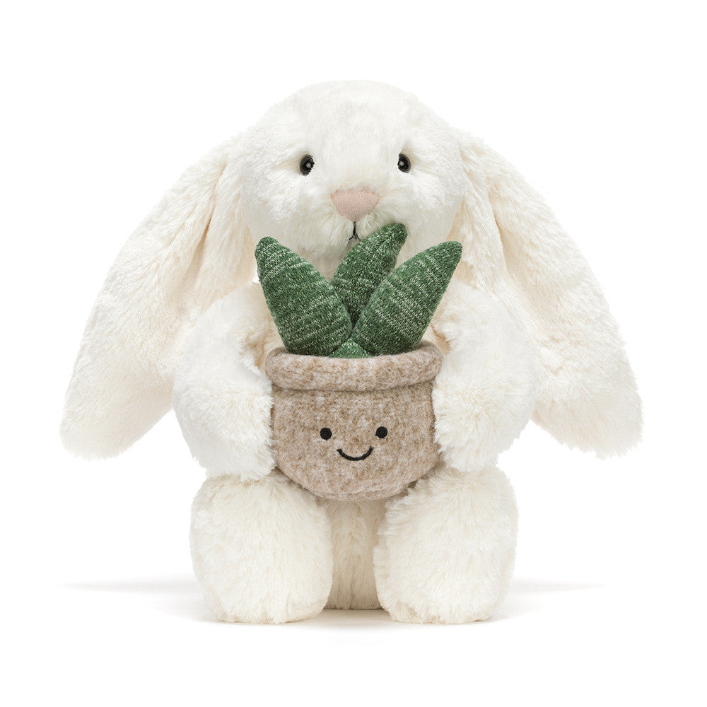 Plush toy rabbit holding a potted plant on a white background