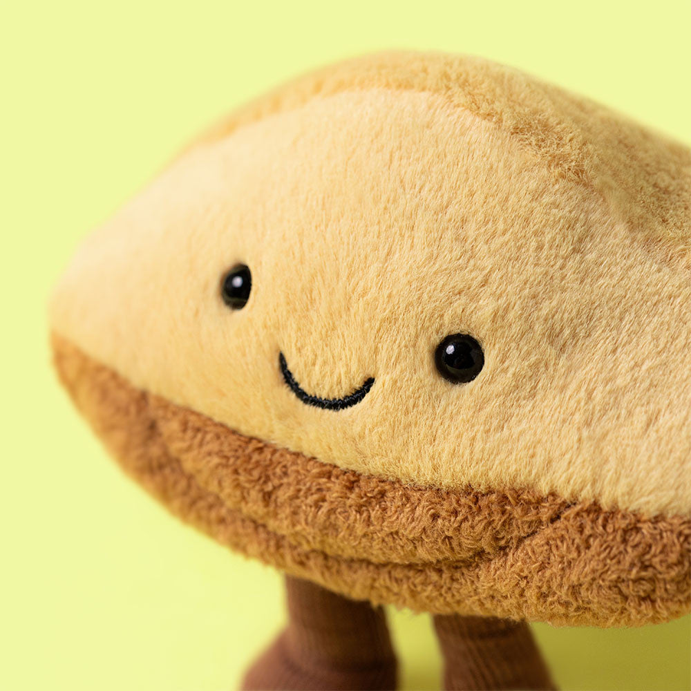 Plush toy resembling a sandwich with a smiley face on a yellow background
