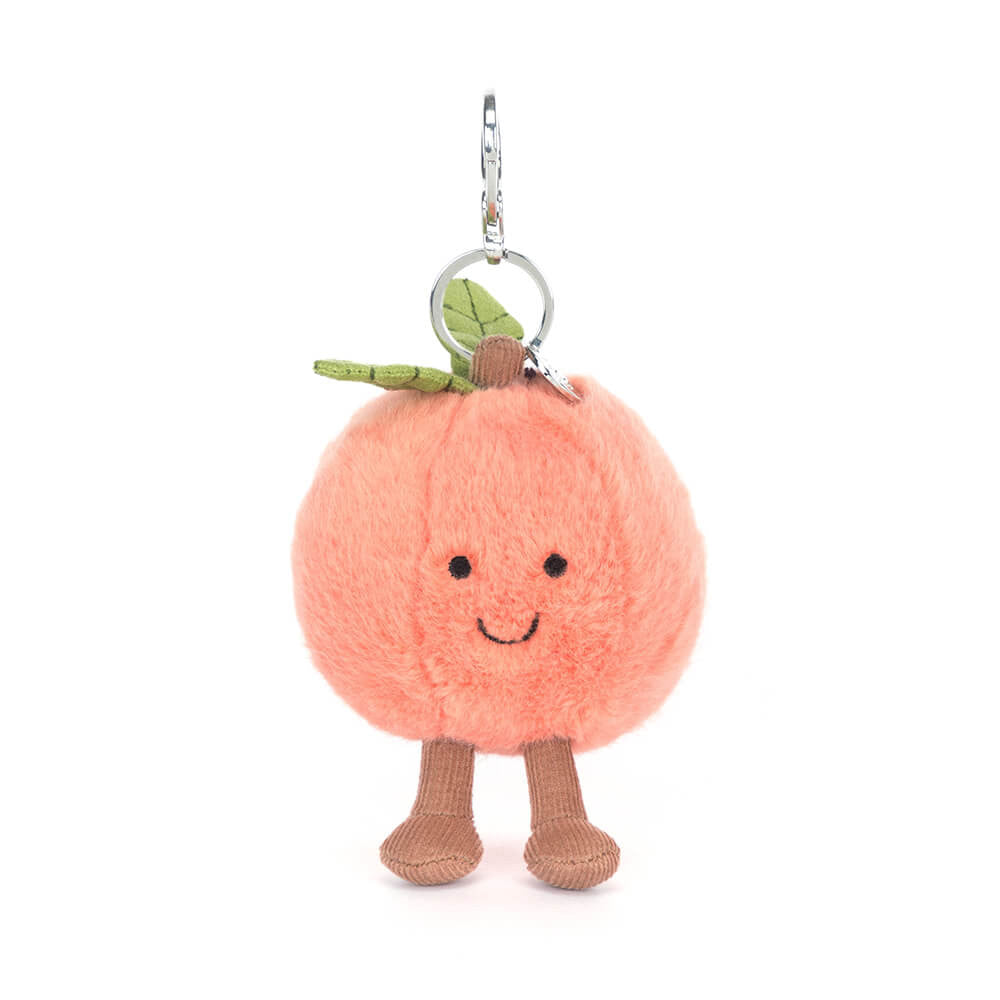 Plush peach keychain with a smiling face on a white background