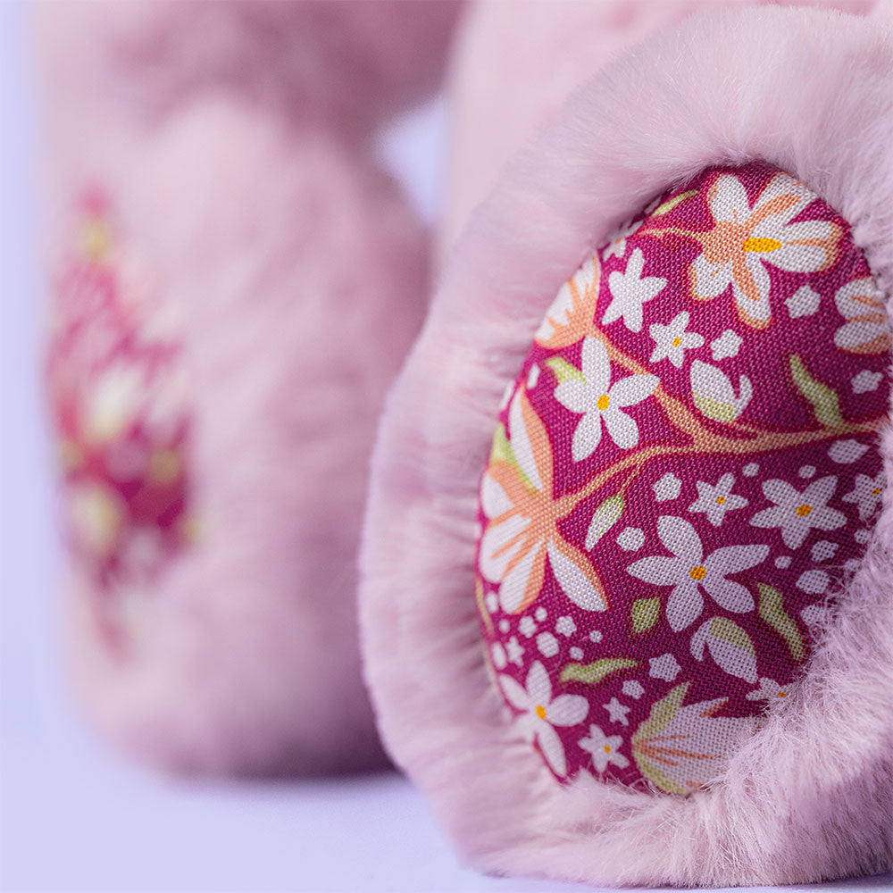 Close-up of pink baby booties with floral pattern on a light background