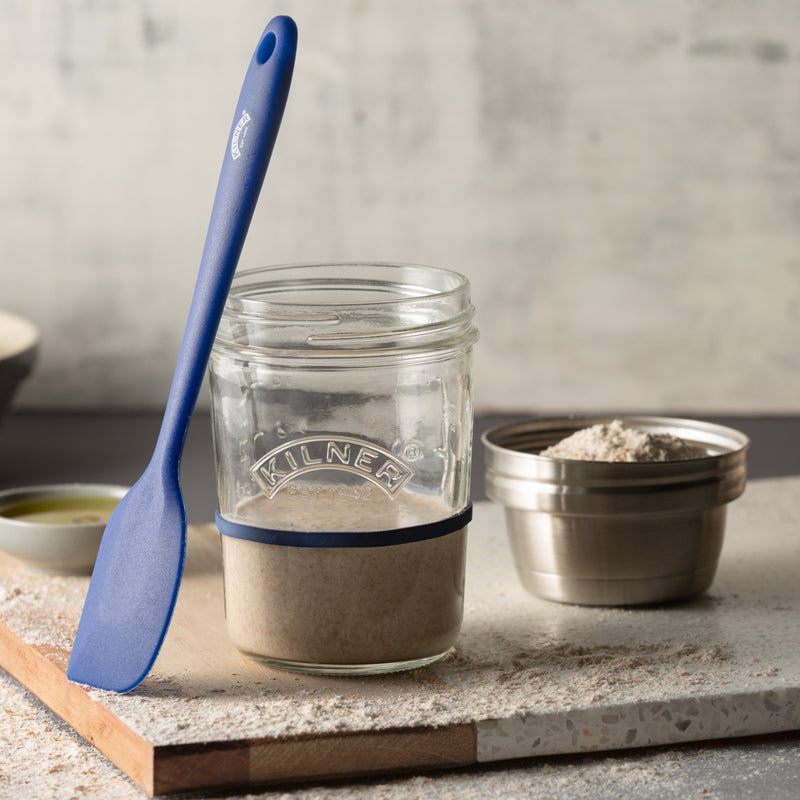 Glass jar with a blue spatula on a countertop