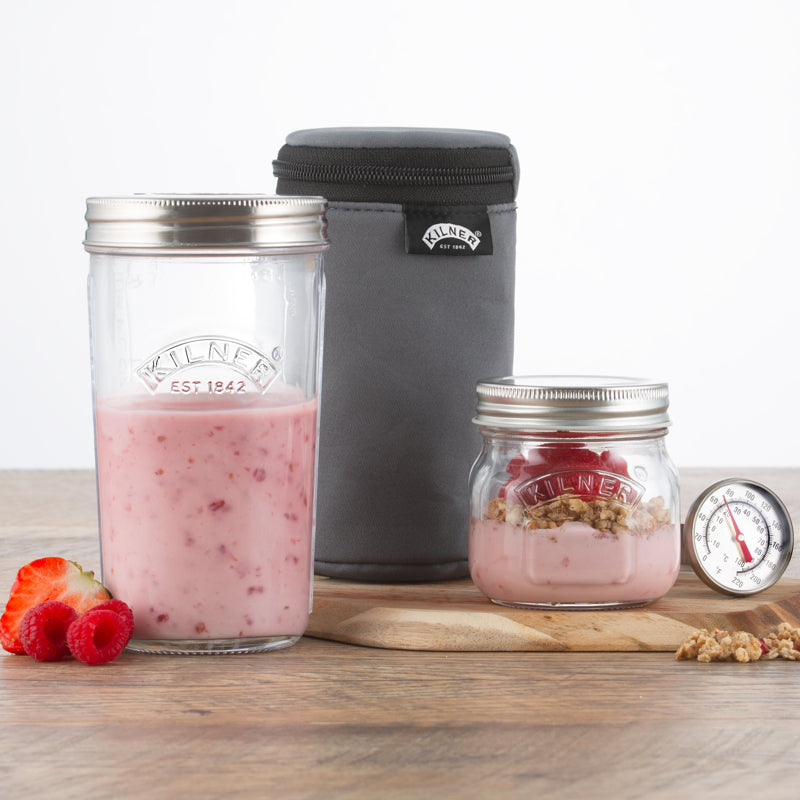 Two glass jars with pink contents and a gray insulated bag on a wooden surface.