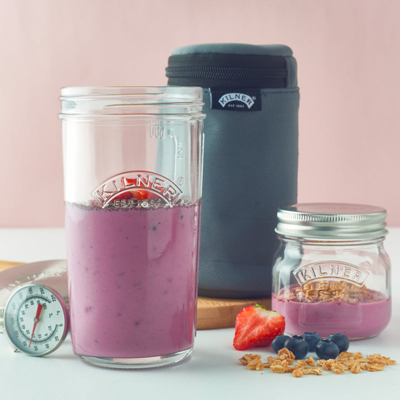 Purple smoothie in a Kilner jar with a thermos and another jar on a light pink background