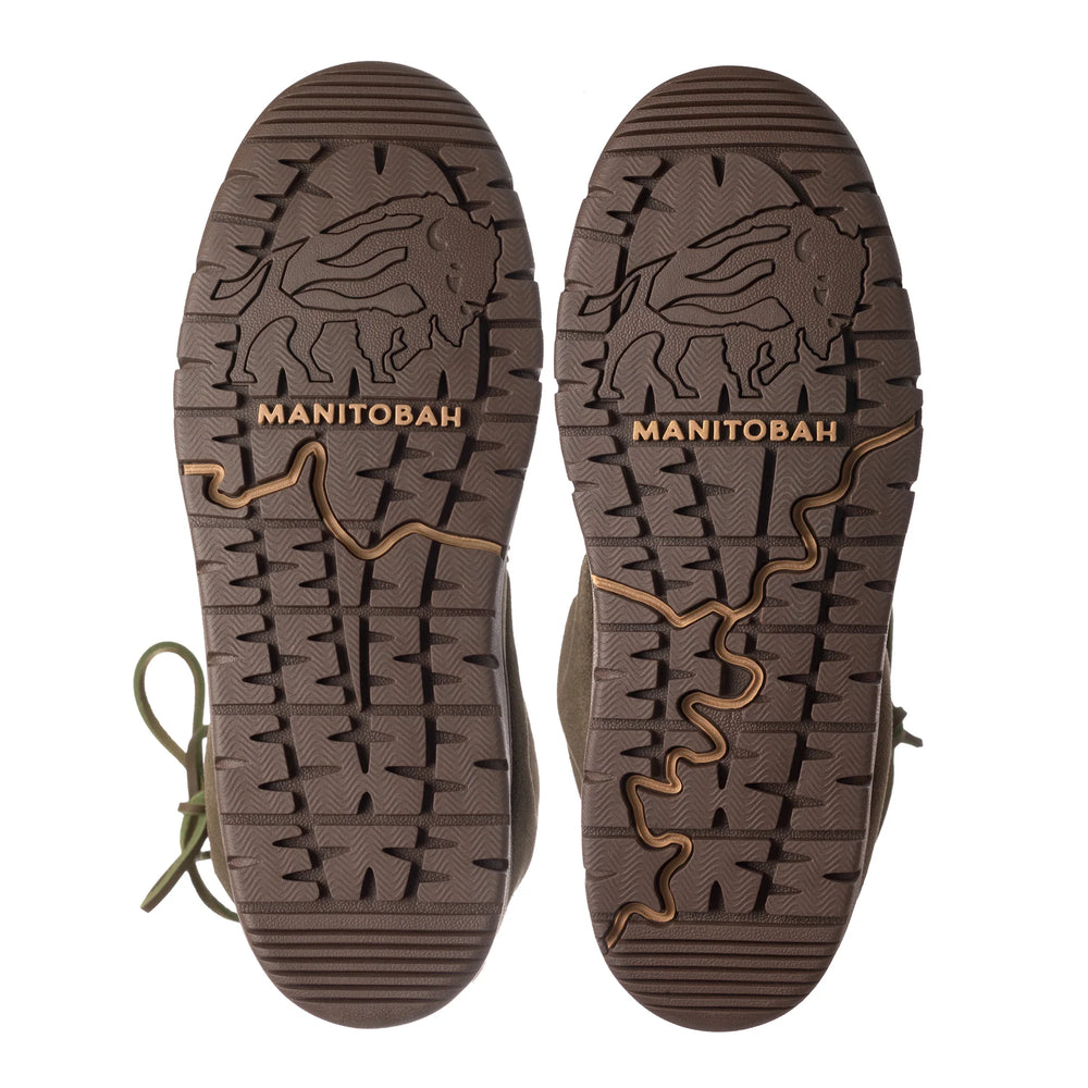 Brown soles of Manitobah boots featuring intricate treads with bison imagery and a winding pattern.
