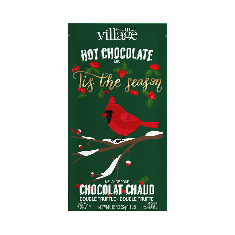 Festive hot chocolate mix package with a red cardinal on snowy branches, surrounded by holly and pine, on a green background. Text: "Tis the season."