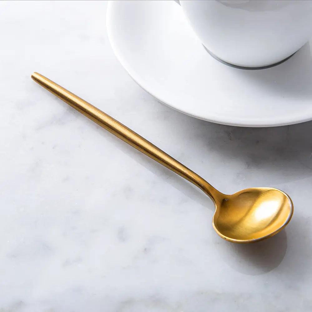 Gold-colored spoon on a marble  background with a coffee cup 