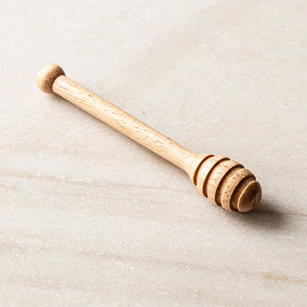 Wooden honey dipper on a light beige surface