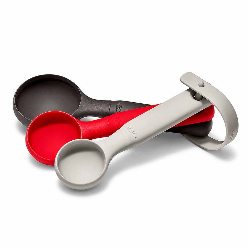 Three silicone measuring spoons in gray, red, and black, arranged in a nested stack on a clean white background.
