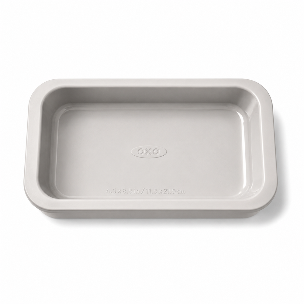 A light gray rectangular ceramic baking pan with rounded corners and a small embossed OXO logo in the center, shown on a clean white background.