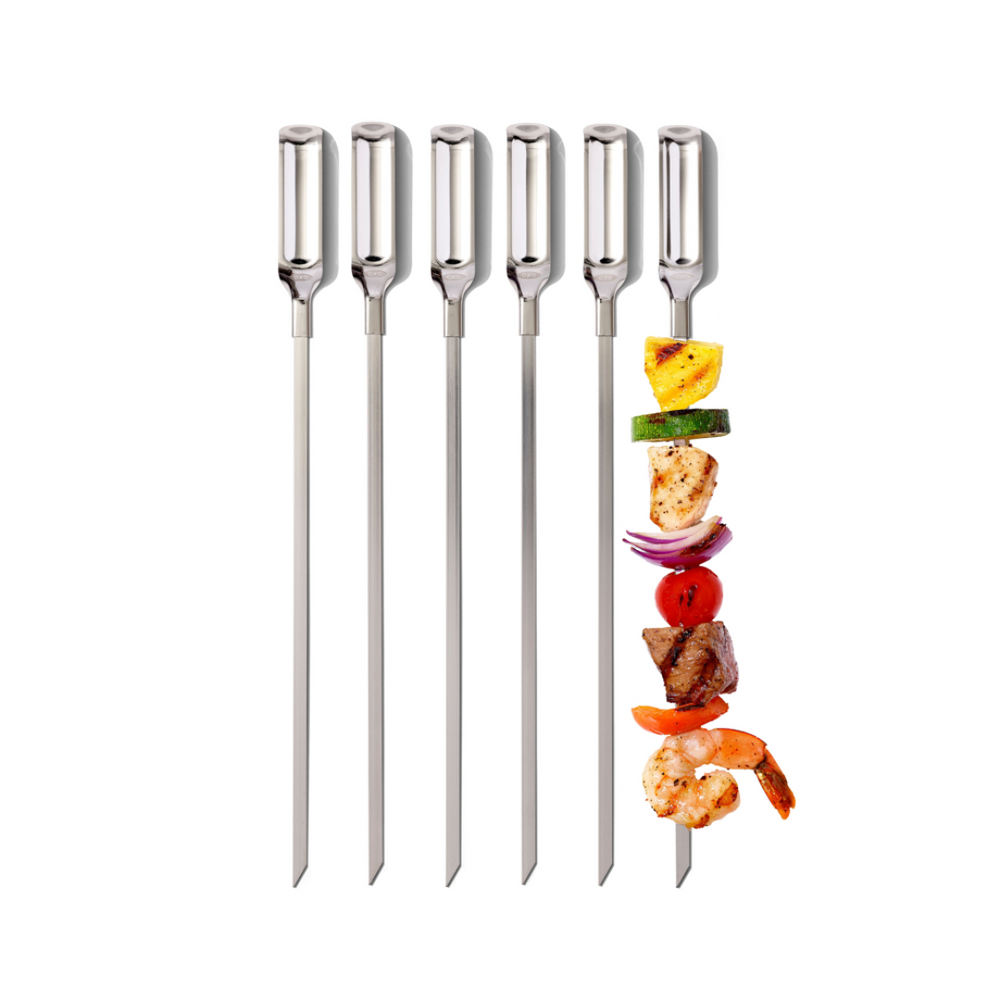 Set of five metal skewers with a skewer of vegetables and meat on a white background