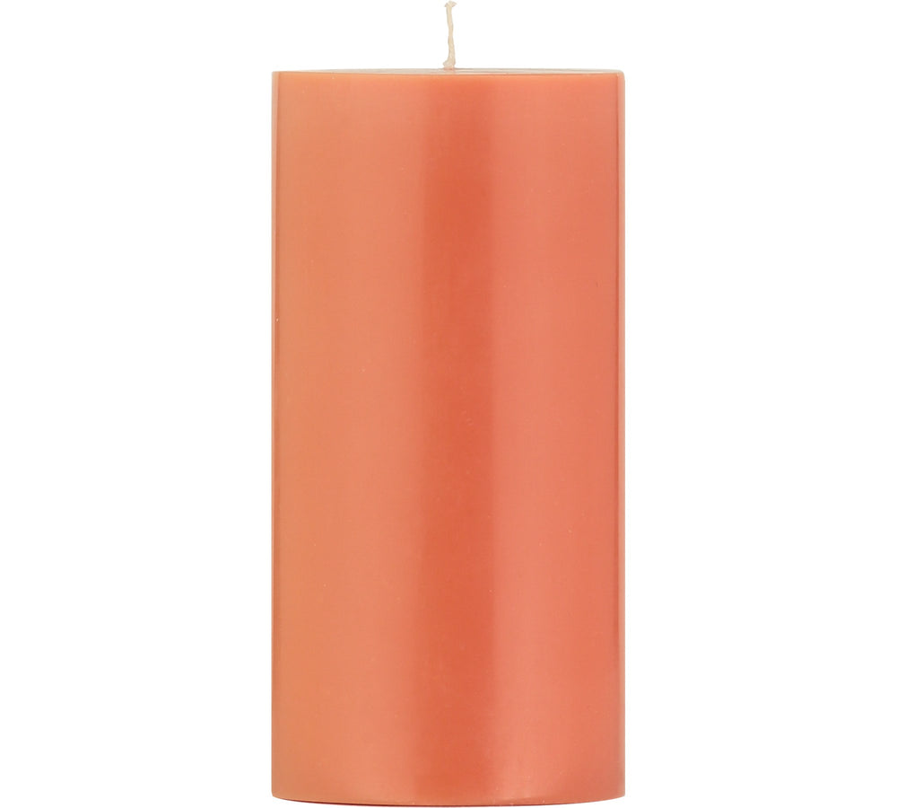 A solid pillar candle with a rust-colored body and a lit flame, placed against a white background.