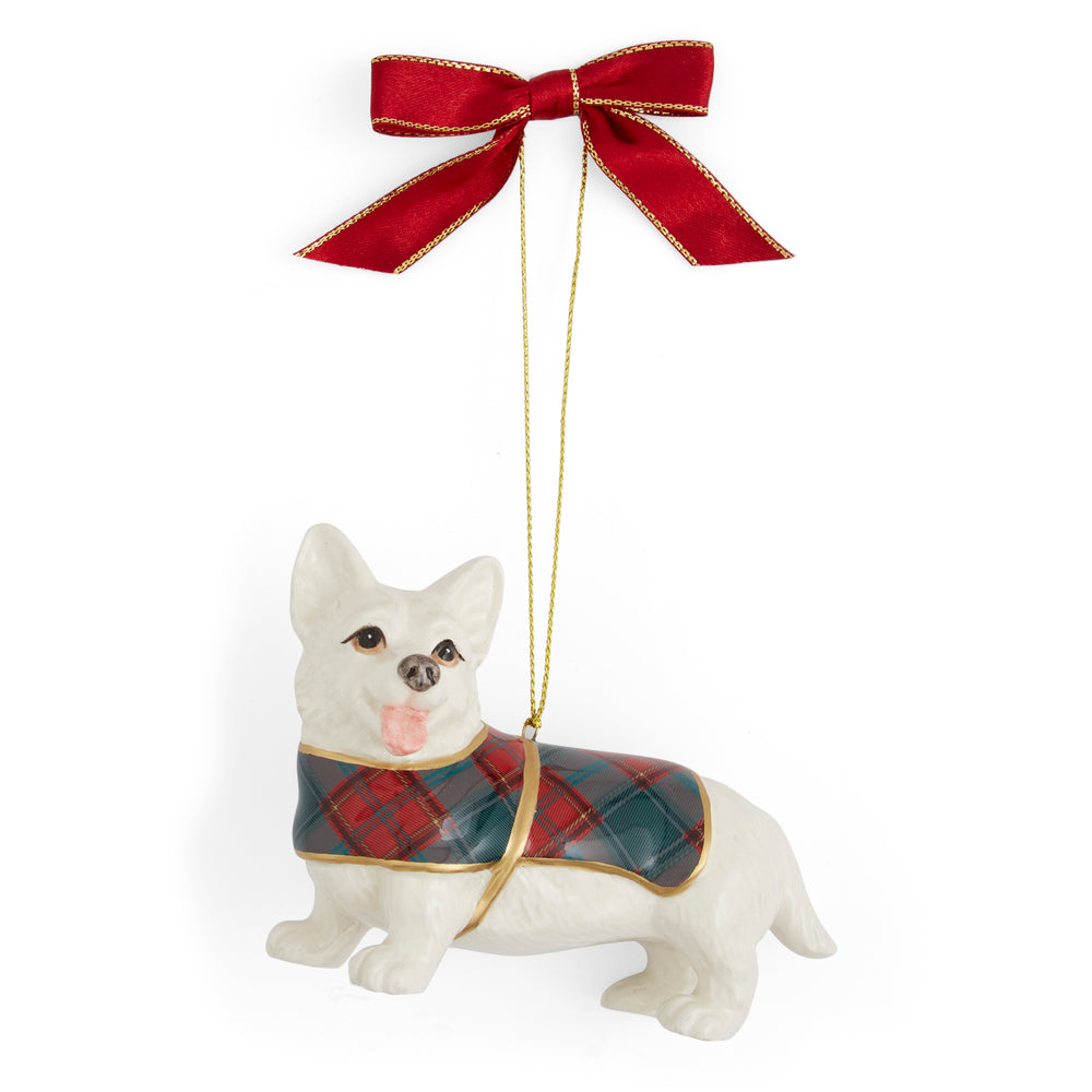 A ceramic Corgi ornament wearing a plaid coat and hanging from a red ribbon with gold trim. The dog has a playful expression with its tongue out.