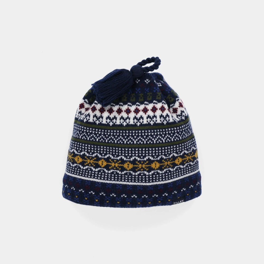A navy blue knit beanie hat featuring a multicolor Fair Isle pattern with white, burgundy, yellow, and green accents, finished with a matching navy blue drawstring and tassel on a light gray background.