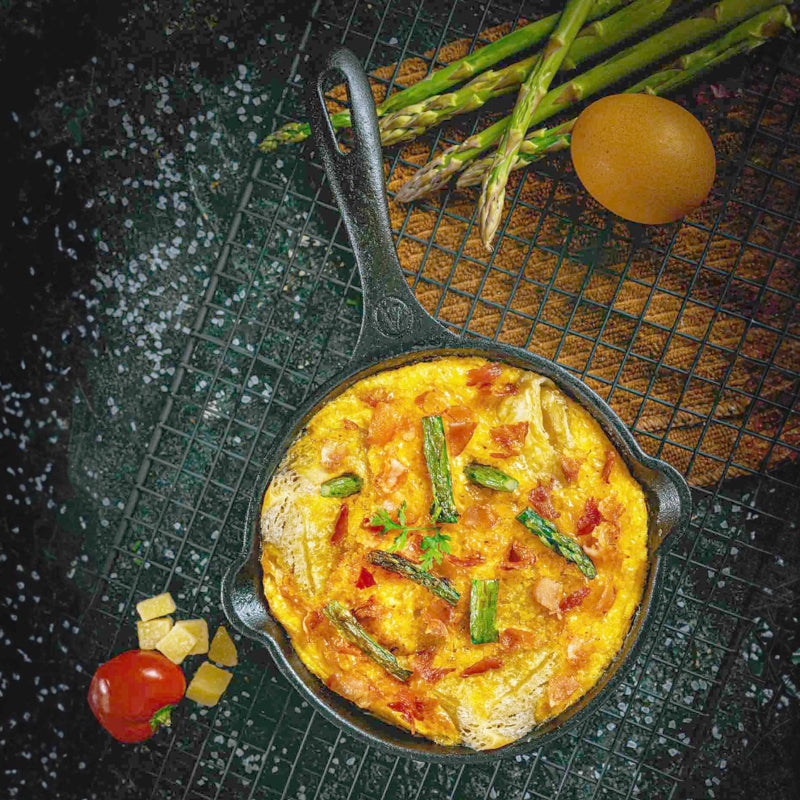 Frittata with asparagus in a cast iron skillet on a dark surface