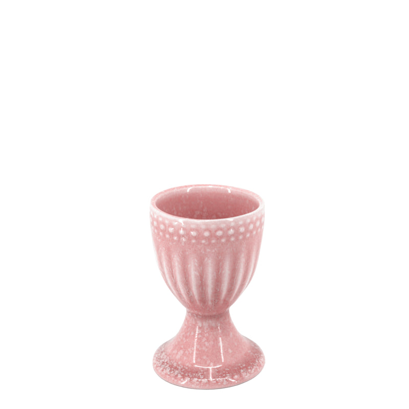 A pink stoneware egg cup with a textured pattern and a reactive glaze finish.